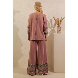 Back view of a woman wearing a mauve leopard print lounge set with a star design, including a long-sleeve top and wide-leg pants, standing outdoors.